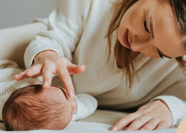 Mutter streichelt liebevoll den Kopf ihres neugeborenen Babys